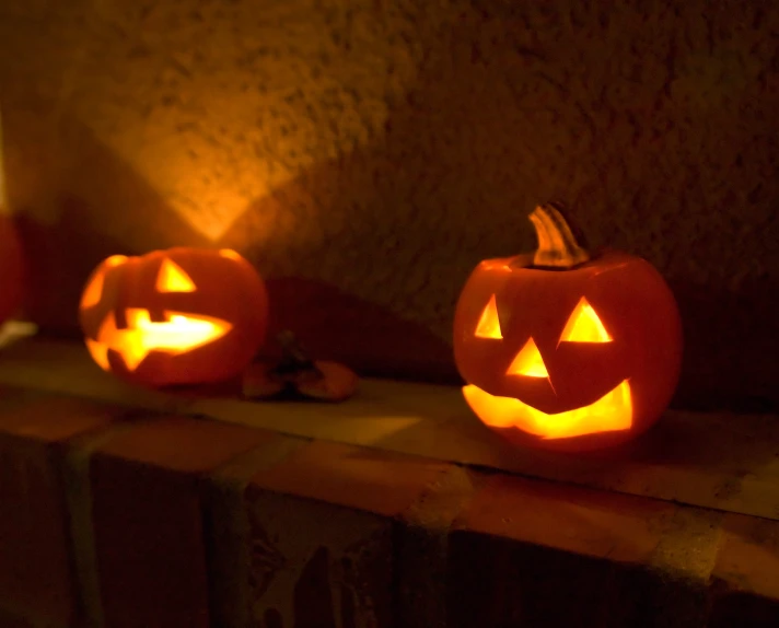 two jack o lanterns are sitting on a mantle