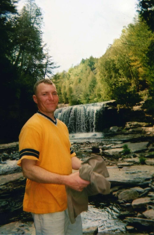 there is a man wearing a hat standing near a creek