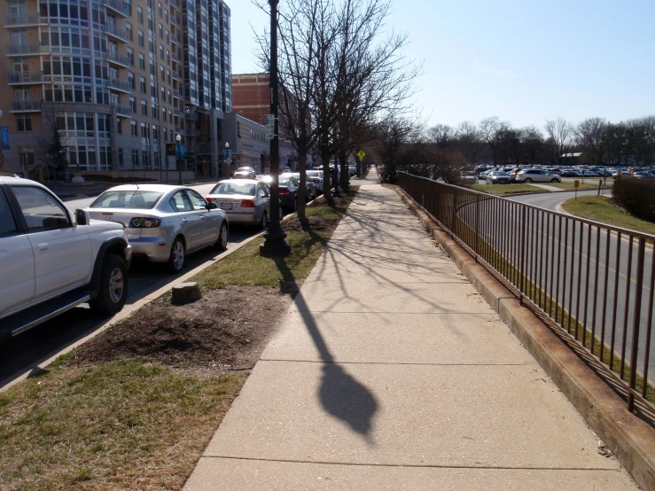 a sidewalk is lined with parked cars in front of an apartment building