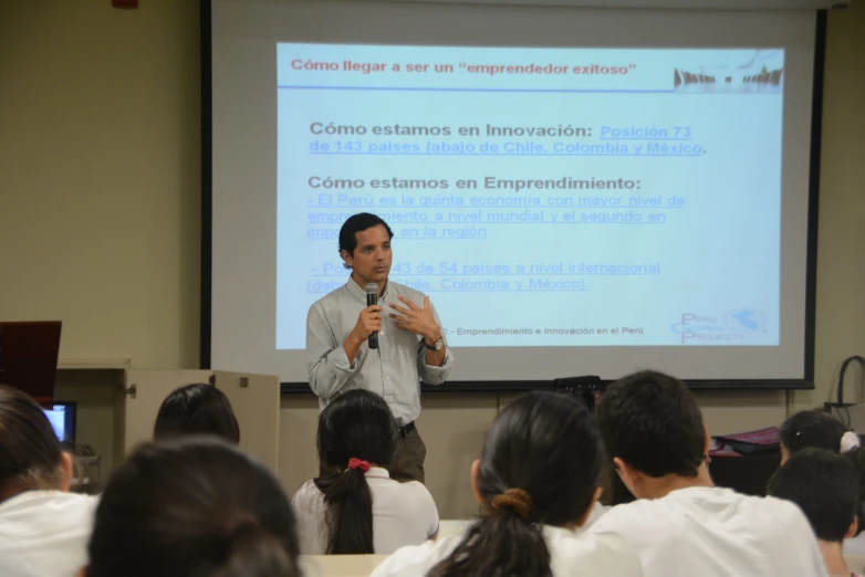 a man stands in front of a class room with a projector