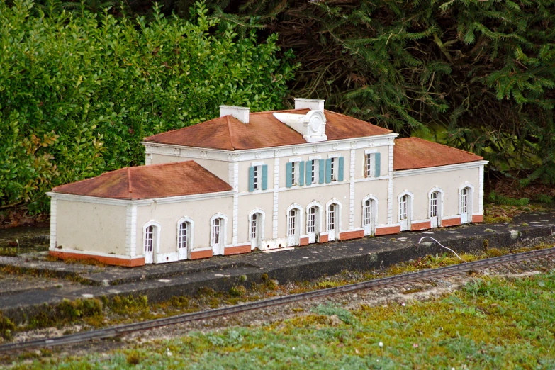 a toy house with cars passing by on tracks