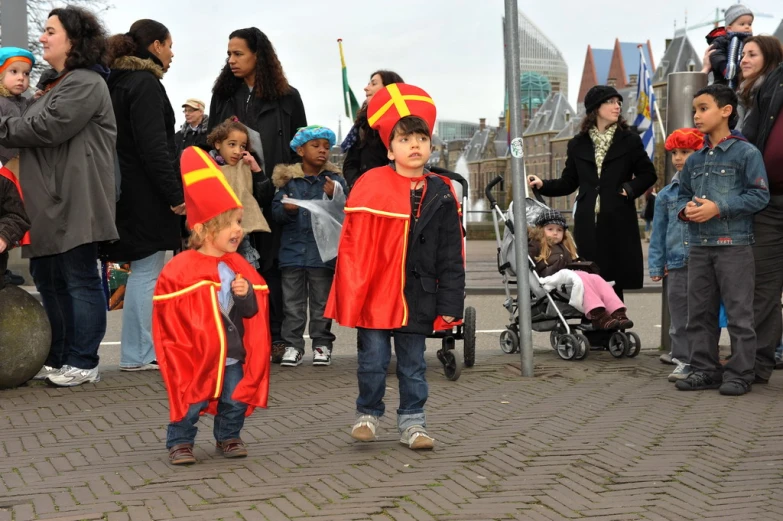 children wearing red and orange robes and walking