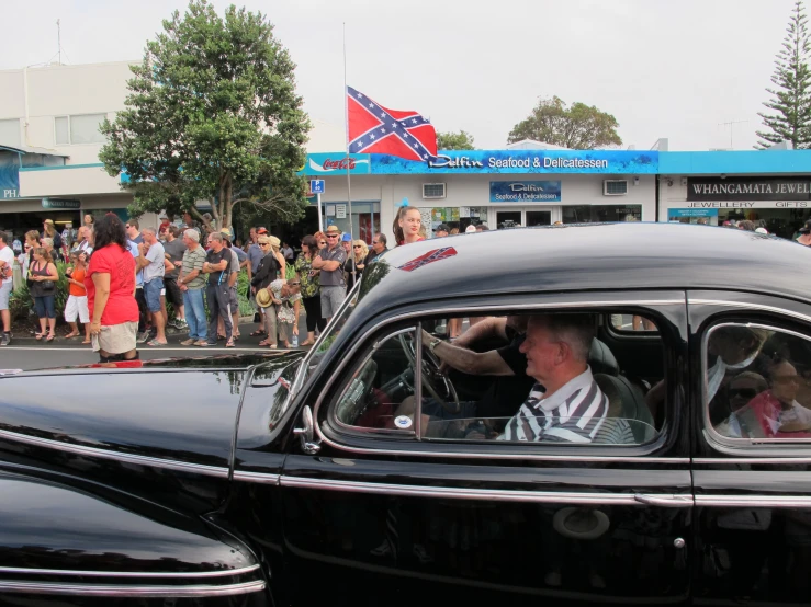 a crowd of people are gathered around an old fashioned car