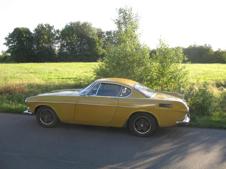 a yellow car parked in the street next to grass