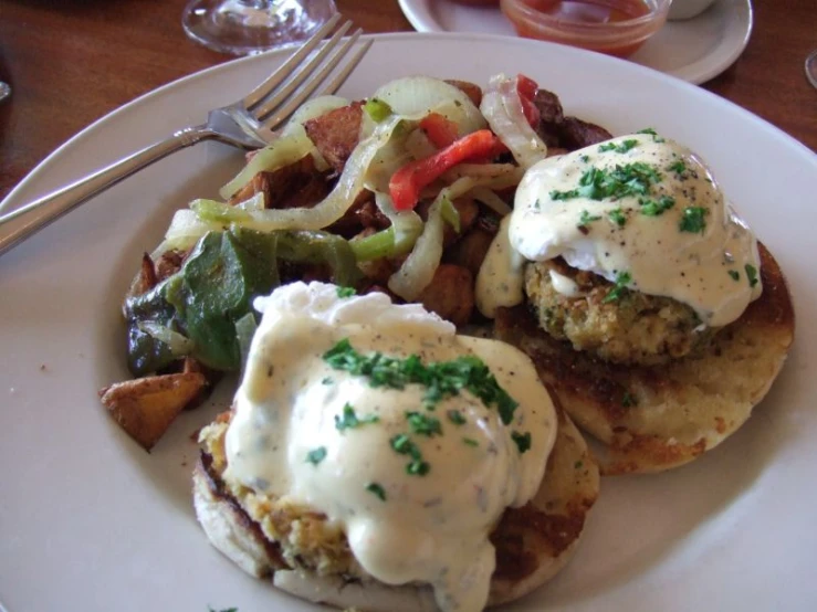 a white plate with two burgers covered in sauce