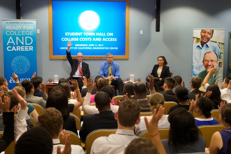 two men and a woman sitting on chairs giving a presentation