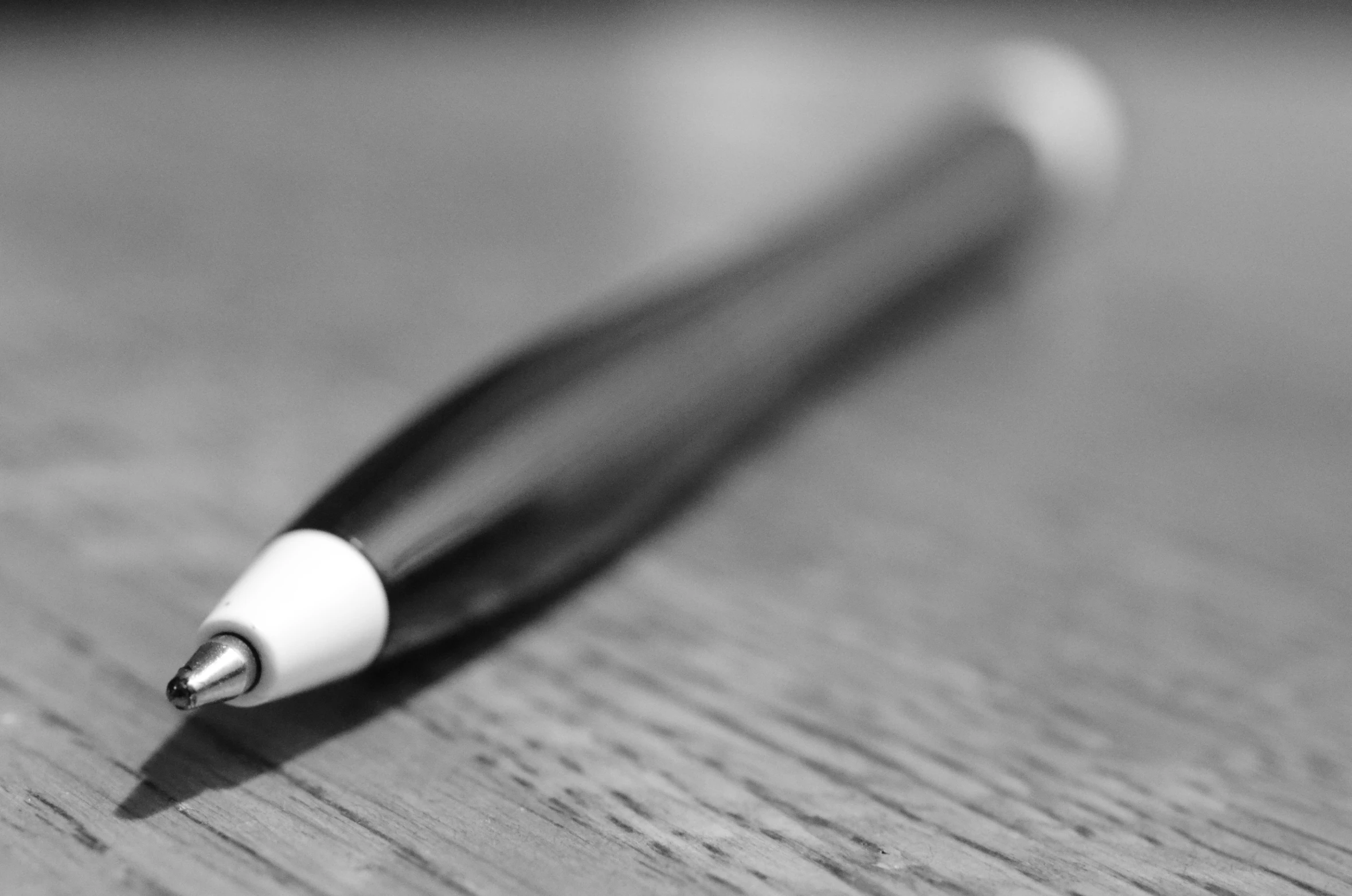 a pen with a black and white tip sits on a wooden surface