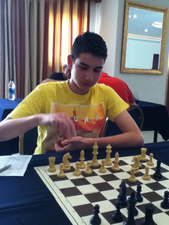 a boy with a yellow shirt on playing chess