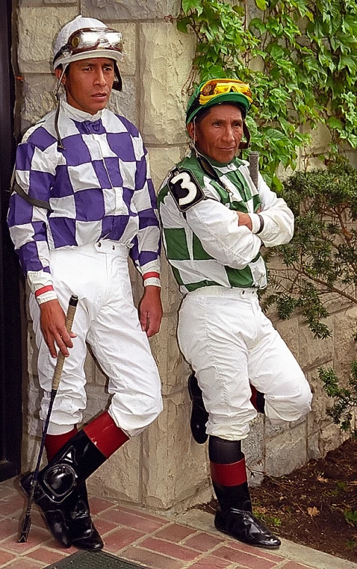 two jockeys in colorful outfits posing for a picture