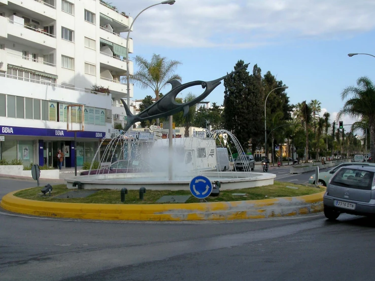 a car driving past a fountain on a city street