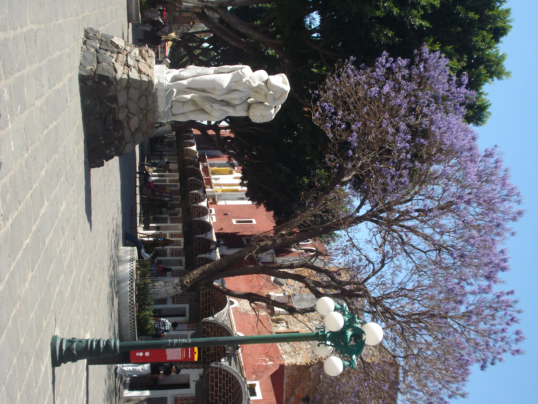 statue on brick paved area near trees and buildings