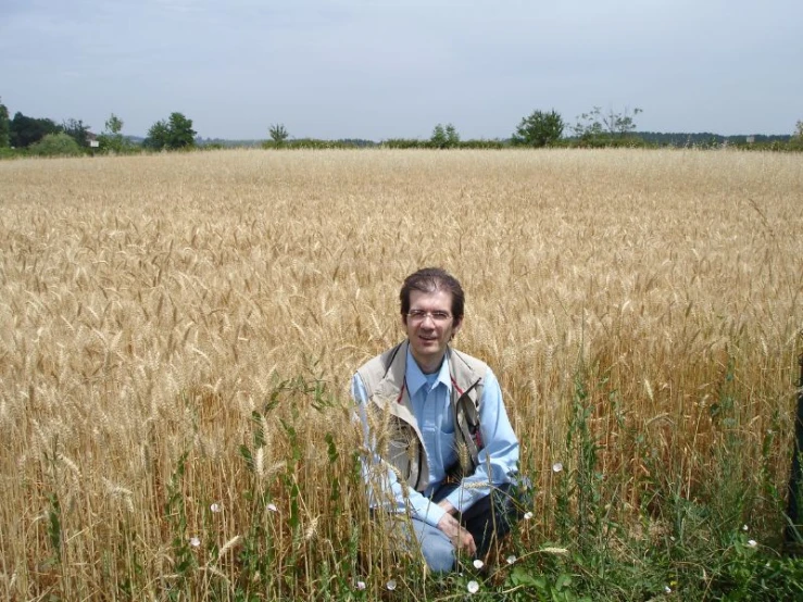 a man crouches on a field with crops