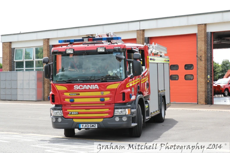 a red and yellow fire truck sitting next to an orange garage