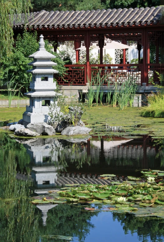 a small white building sitting next to a pond