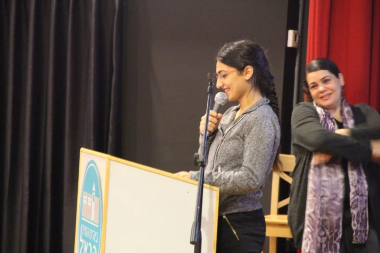 two women speak in front of a podium at a conference