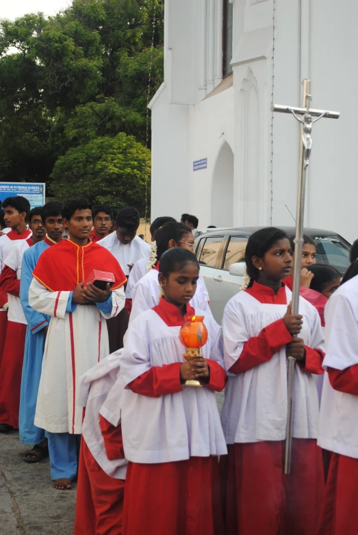 children dressed in red and white are holding a staff