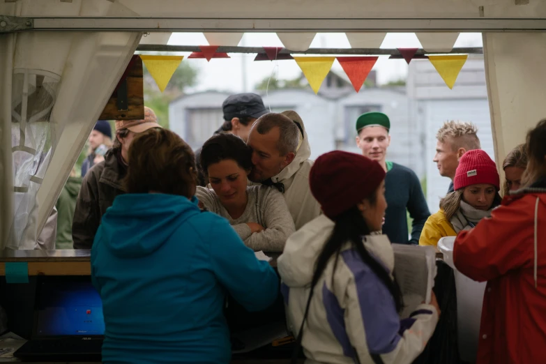 people are standing around and eating inside a tent