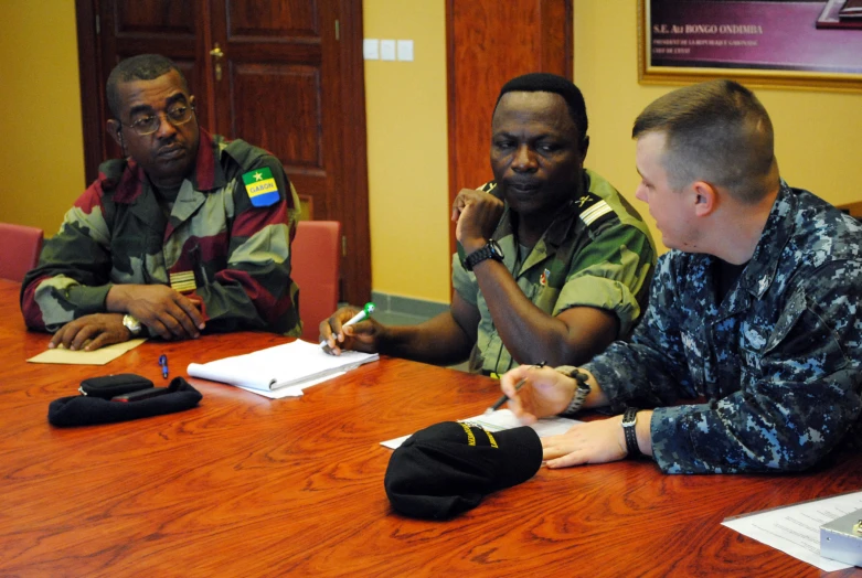 men in uniform are around a table and talking