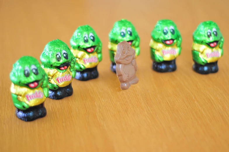 some little figurines with green gummy bears and a cat