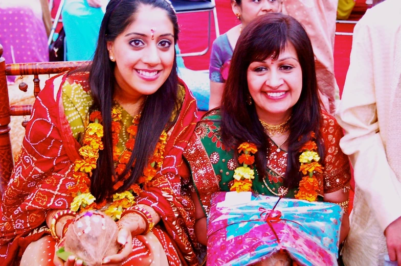 two women are sitting on the ground wearing traditional indian dresses