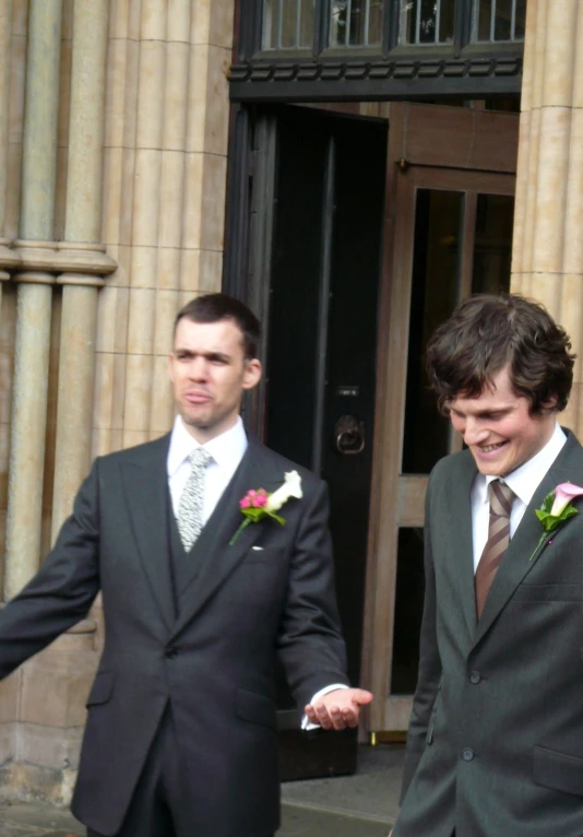 two men in suits walk toward a building