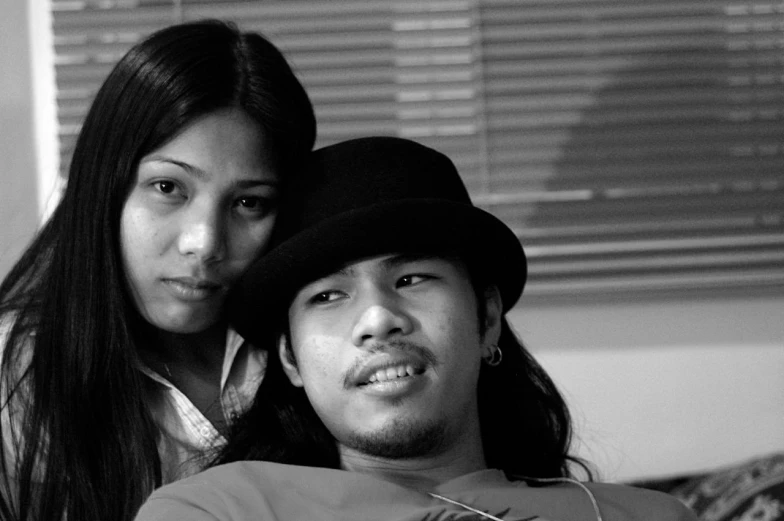 a young man with long hair and a women's hat poses for a black and white po