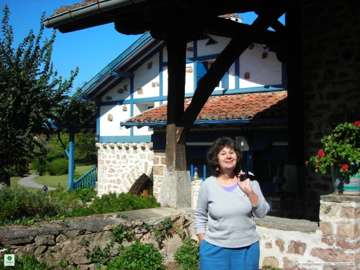 a woman holding a glass is standing in front of an old - fashioned building