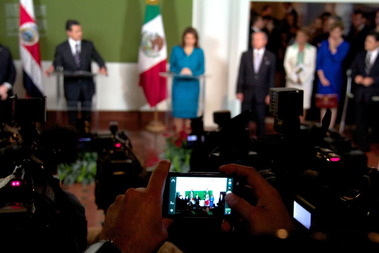 people with cameras take pictures while president obama gives a speech