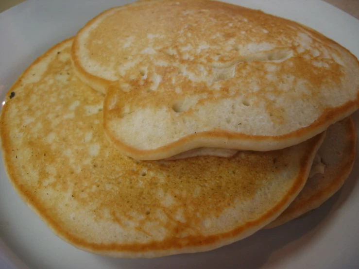 several pancakes on a white plate stacked high