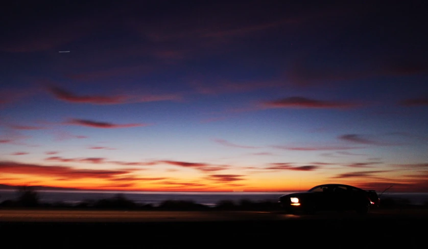 the car is moving along the roadway in the evening