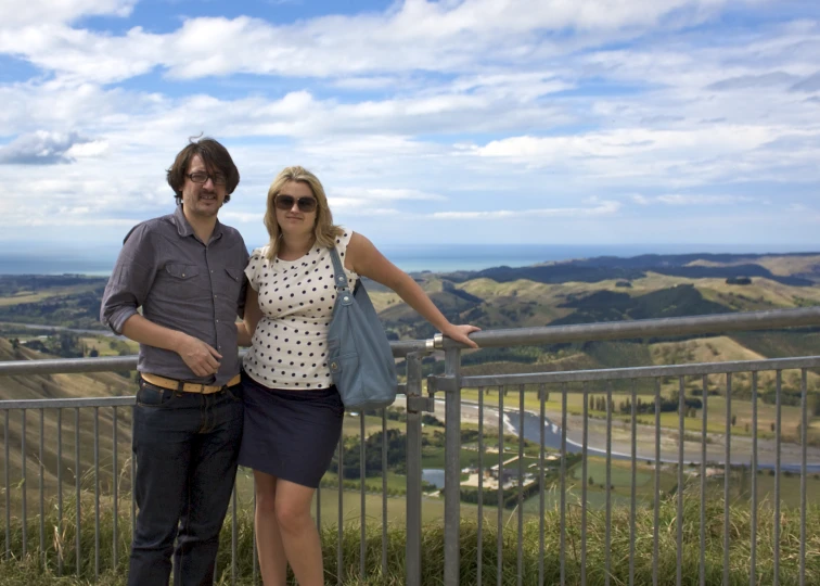 a man and woman standing next to each other by a fence