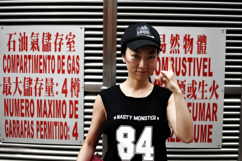 a person wearing a black cap and t - shirt and standing in front of some signs