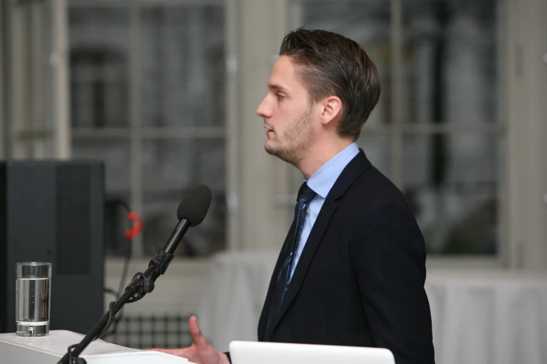 a man speaking with a microphone and a laptop