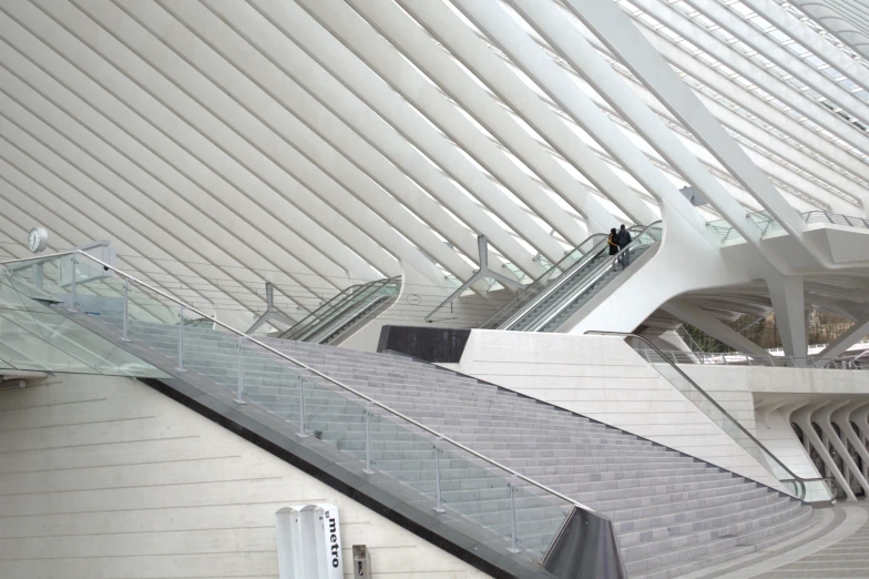 escalators inside a building with a roof and metal railing