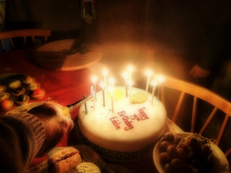 a birthday cake with a few candles in the center, surrounded by fruit and cookies