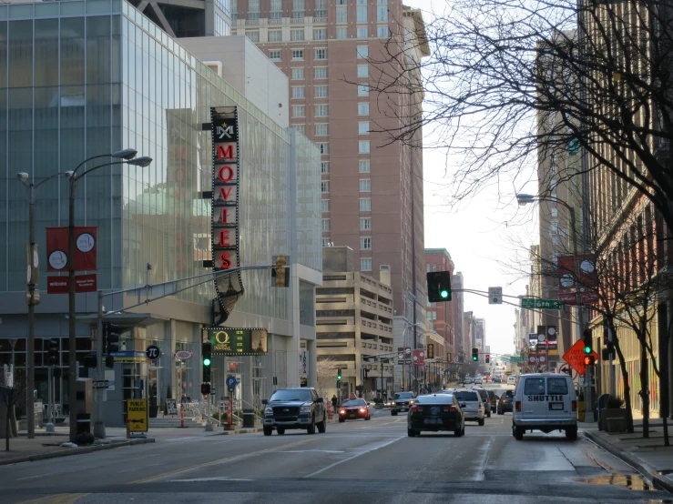 the cars are driving down the street next to tall buildings