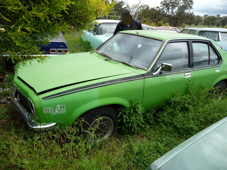 several cars parked in the grass with one upside down