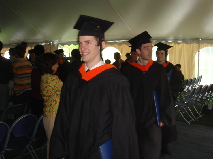 a graduate standing next to other graduates in their caps and gowns