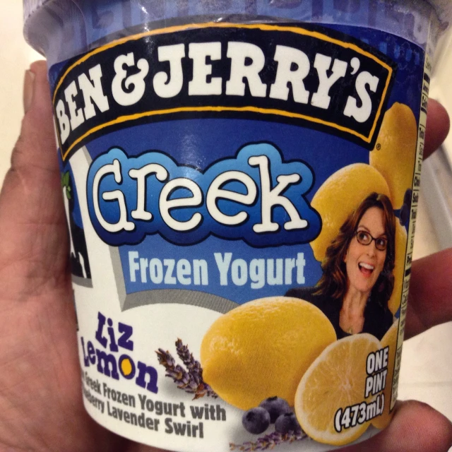 a person holding up a container of ice cream that has been decorated with lemon and blueberries