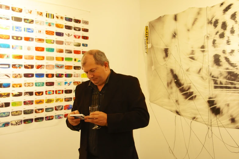 a man looking at a cell phone while standing in front of a picture