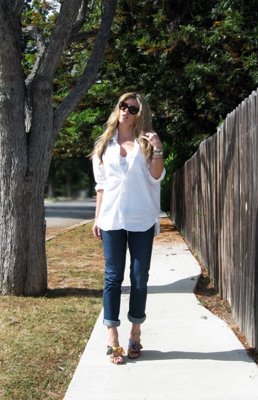 a woman walking down a sidewalk carrying a cellphone