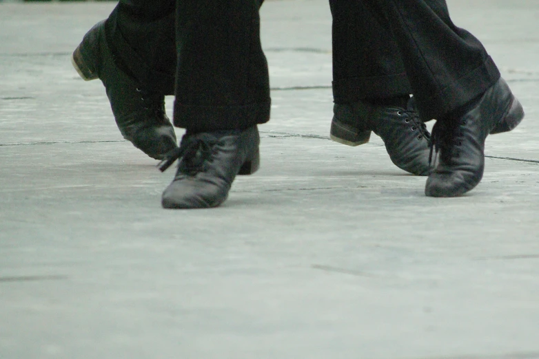 closeup of two people's shoes and pants on concrete