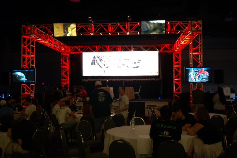 a crowd is gathered underneath an electronic screen at an event