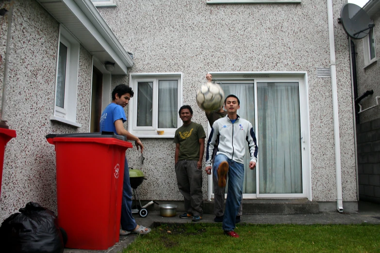 four men standing on the grass outside of a house