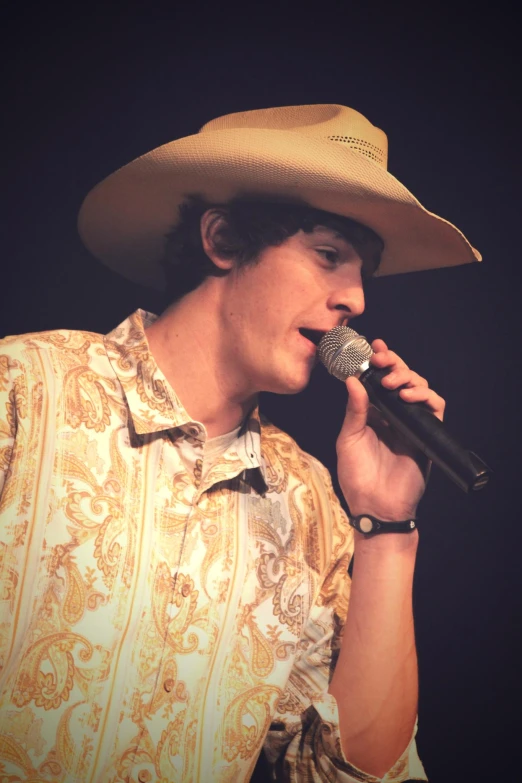 a man wearing a cowboy hat holding a microphone