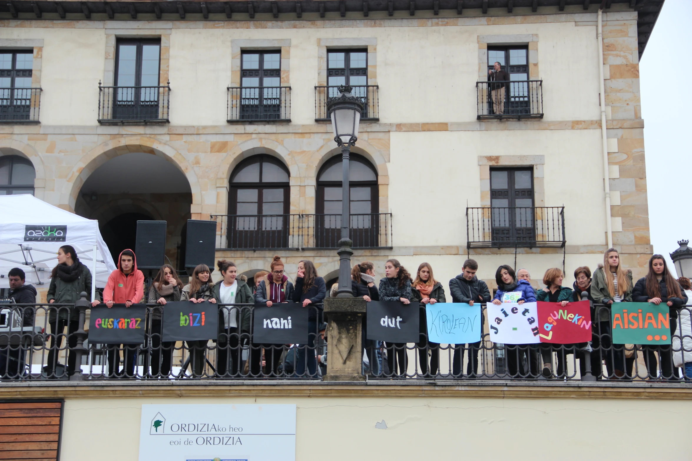 many people holding protest signs on the balcony