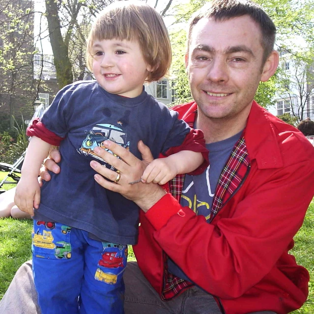 a man in red jacket holding a small child