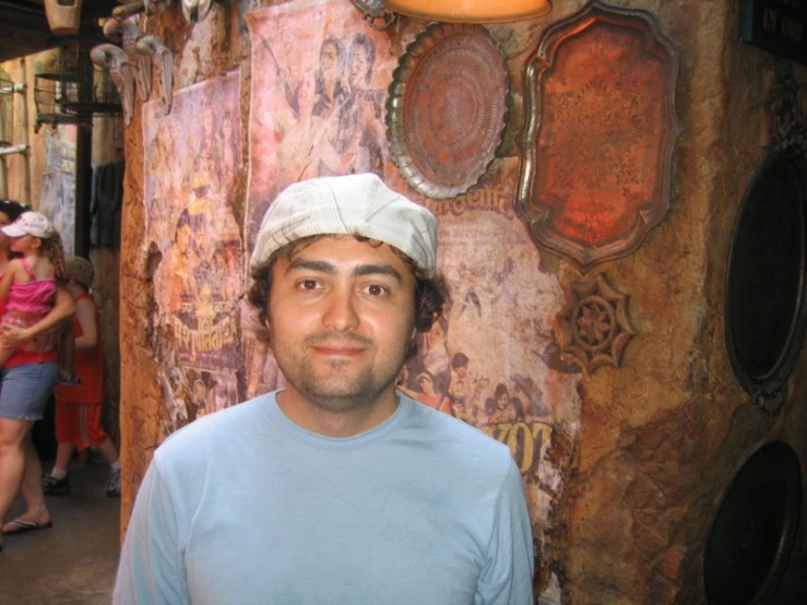 a man is standing next to a wall covered in paintings