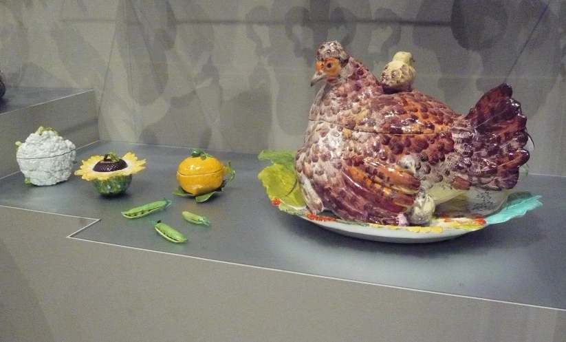 a stuffed chicken sitting on a table next to some plastic fruit