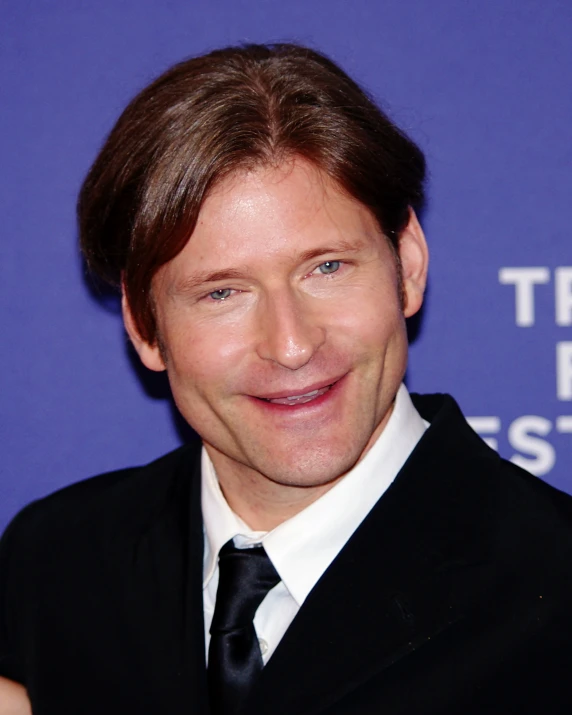 a person with a black tie and suit smiling